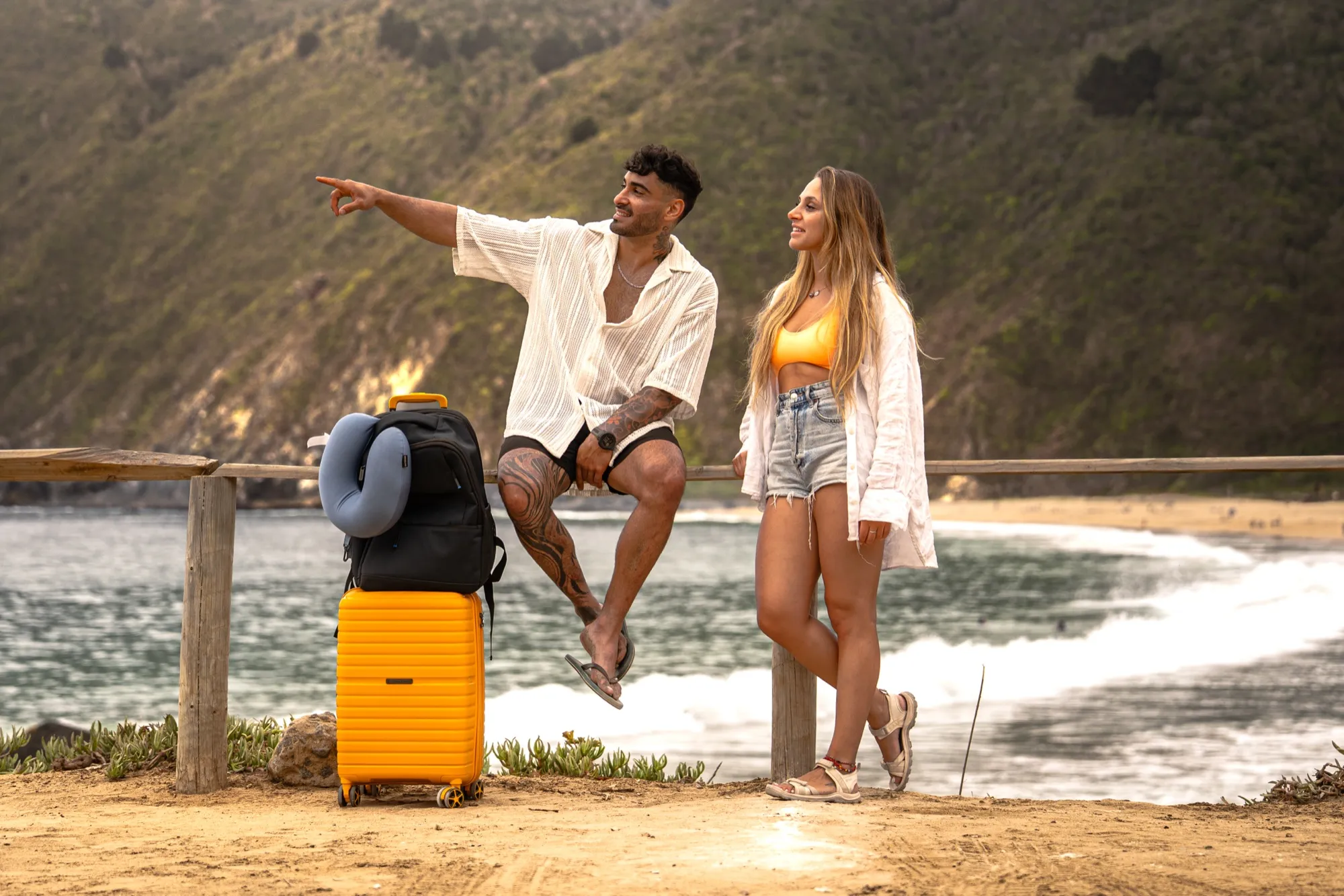Pareja en un mirador junto al mar con una maleta amarilla Saxoline