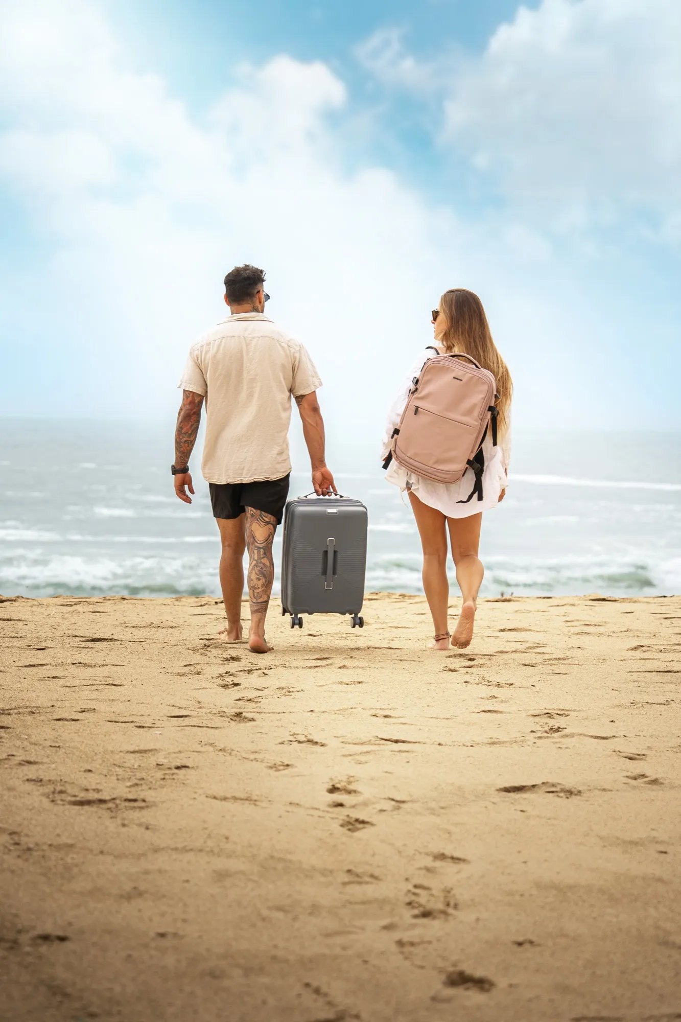 Pareja con maleta y mochila Saxoline en la orilla