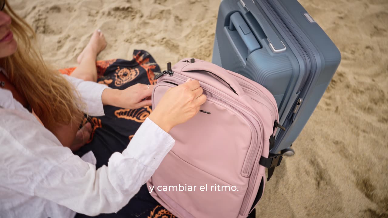 Mochila rosada y maleta de Saxoline sobre la arena de la playa