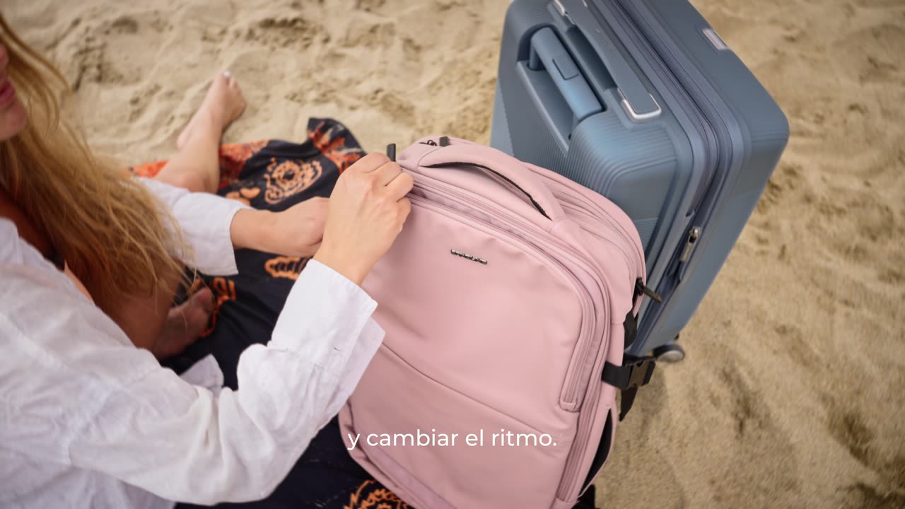 Mochila rosada y maleta de Saxoline en la playa, versión alternativa